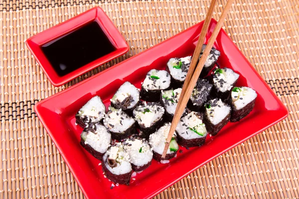 Vegetarian sushi roll served on a red plate — Stock Photo, Image