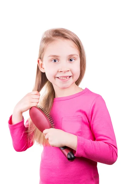 Porträtt av en vacker liten flicka borsta hennes långa hår. hår vård koncept. — Stockfoto