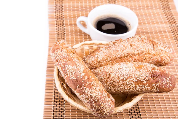 Rolos de pão recém-assados com gergelim com xícara de café — Fotografia de Stock