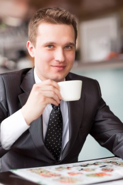 Genç yakışıklı işadamı kahve içiyor.