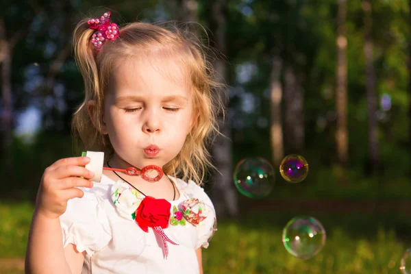 Beautiful little girl blowing soap bubbles — Stock Photo, Image