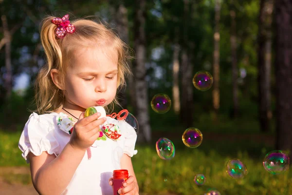 Beautiful little girl blowing soap bubbles — Stock Photo, Image