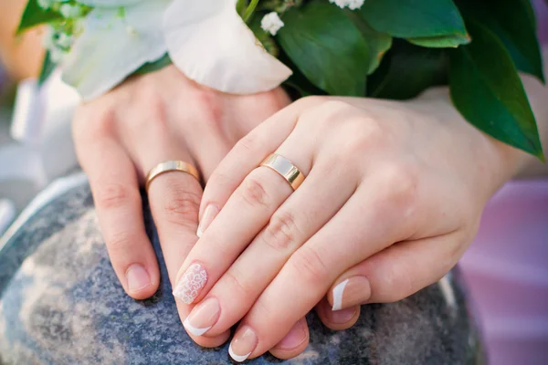 Hände von Braut und Bräutigam und Ringe mit Brautstrauß — Stockfoto