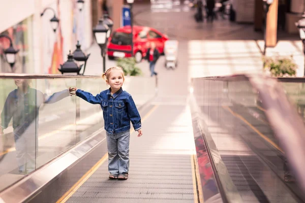 Lindo niño pequeño en el centro comercial de pie en la escalera mecánica en movimiento — Foto de Stock