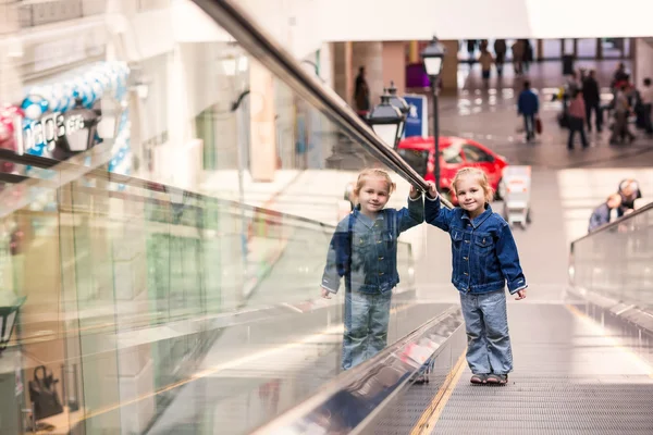 Lindo niño pequeño en el centro comercial de pie en la escalera mecánica en movimiento — Foto de Stock