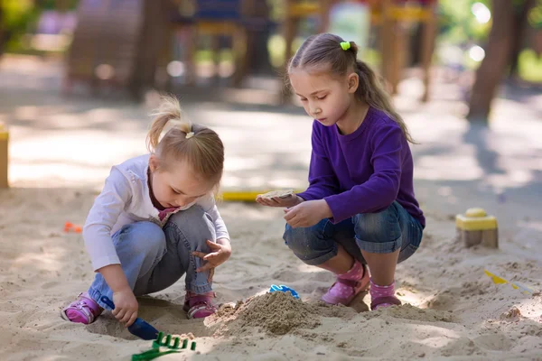 Happy little girls playing in a sendbox — Stock Photo, Image