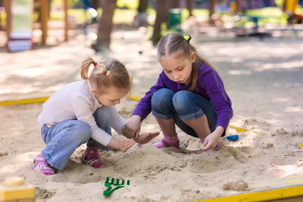 Gelukkig weinig meisjes spelen in een sendbox — Stockfoto