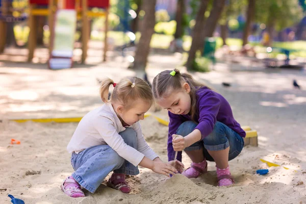 Meninas pequenas felizes jogando em um sendbox — Fotografia de Stock