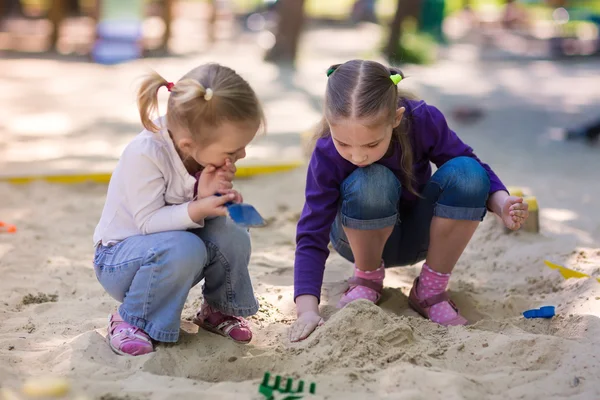 Happy little girls playing in a sendbox — Stock Photo, Image