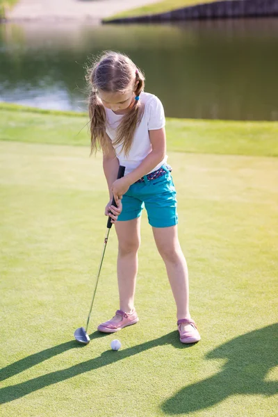 Linda niña jugando al golf en un campo Imágenes de stock libres de derechos