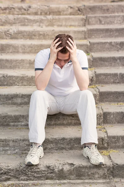 Frustrated stressed young man sitting on stairs — Stock Photo, Image