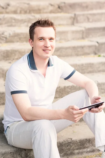 Ung man sitter på en trappa med TabletPC — Stockfoto