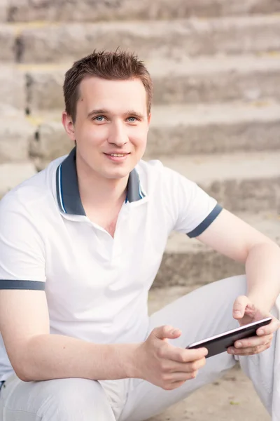 Junger Mann sitzt mit Tablet-PC auf einer Treppe — Stockfoto