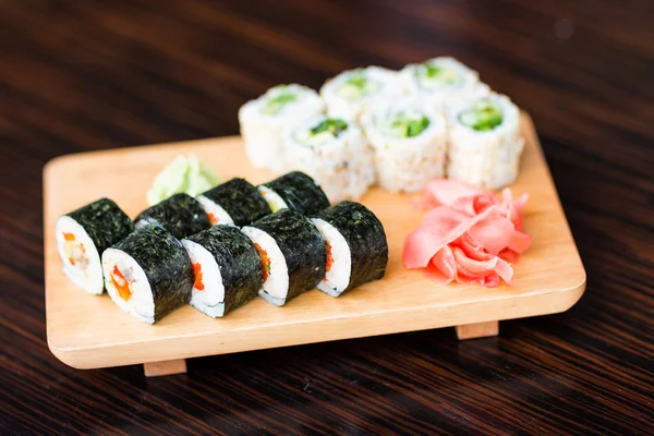 Rolos de sushi servidos em uma placa de madeira — Fotografia de Stock