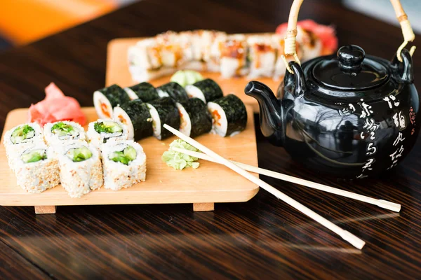 Rolos de sushi servidos em uma placa de madeira — Fotografia de Stock