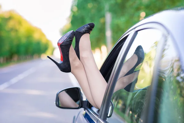 Woman's legs in highheel shoes out of a car window — Stock Photo, Image