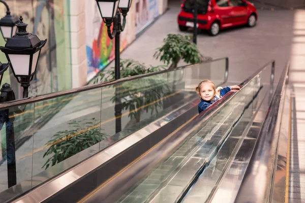 Criança bonito no centro comercial na escada rolante — Fotografia de Stock