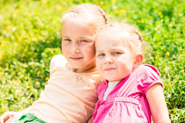 Två leende små flickor på ängen — Stockfoto