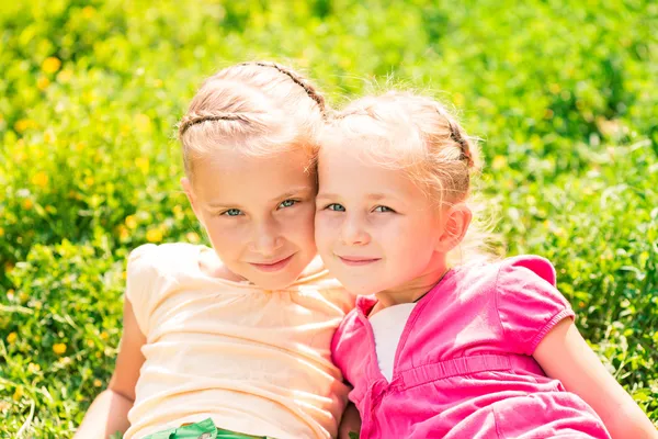 Två leende små flickor på ängen — Stockfoto