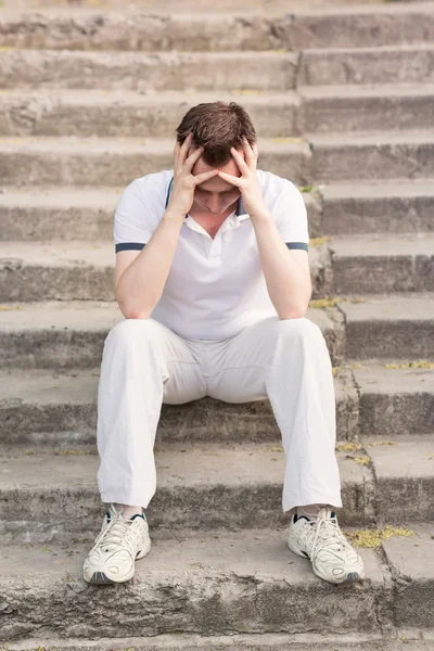 Frustrated stressed young man sitting on stairs — Stock Photo, Image