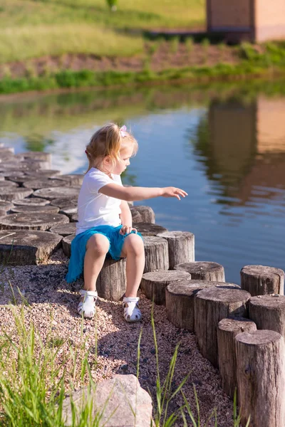 Söt liten flicka sitter nära sjön — Stockfoto
