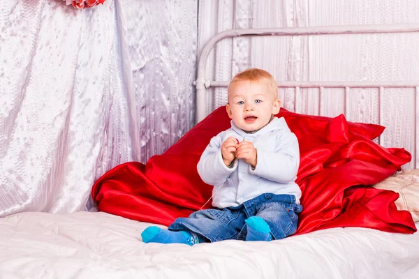 Niedliche kleine Junge auf einem Bett spielen — Stockfoto