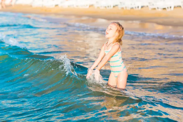 Adorable niña jugando en el mar en una playa —  Fotos de Stock