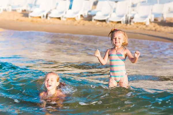 Two adorable kids playing in the sea on a beach — Stock Photo, Image