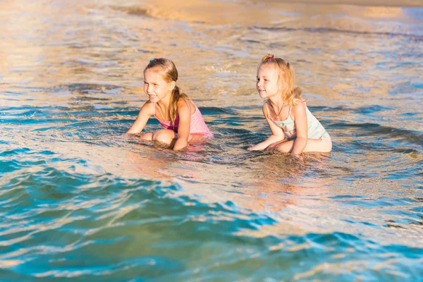 Two adorable kids playing in the sea on a beach — Stock Photo, Image