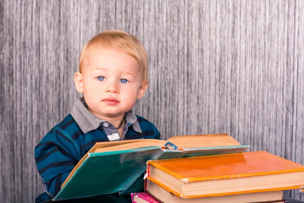 Очаровательный мальчик с грудой книг — стоковое фото