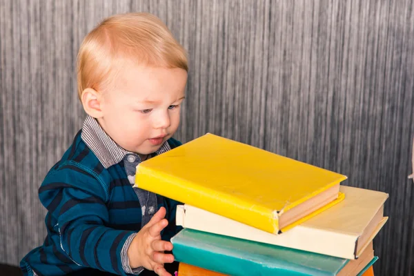 Adorable baby boy with a pile of books — Stock Photo, Image