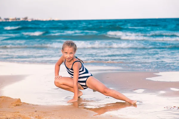 Schönes kleines Mädchen beim Turnen am Strand — Stockfoto