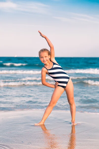 Beautiful little girl excercising on the beach — Stock Photo, Image