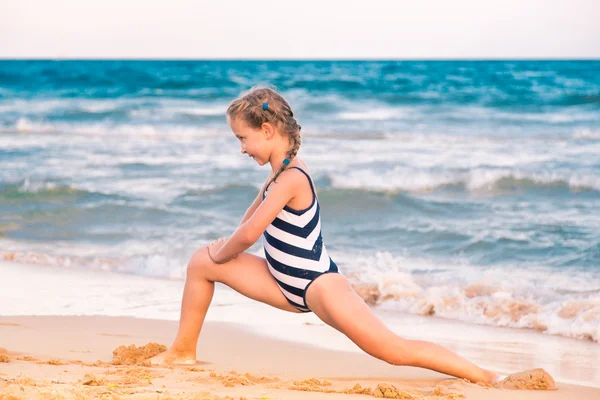 Mooie kleine meisje beoefenen op het strand — Stockfoto