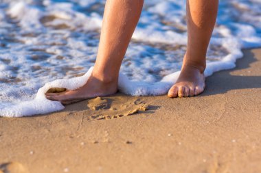 deniz kıyısı boyunca çıplak ayakları ile yürüyen çocuk