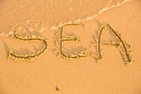 Slovo moře na žluté písečné pláži — Stock fotografie