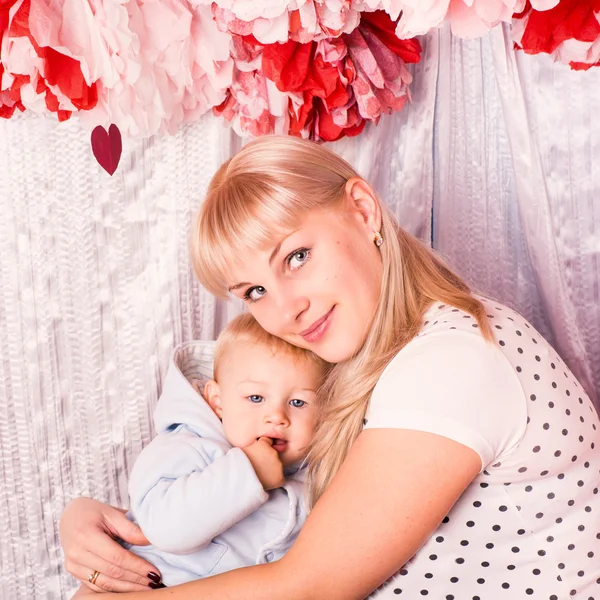 Beautiful happy mother hugging baby on a bed — Stock Photo, Image