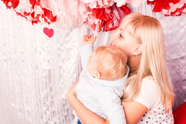 Beautiful happy mother hugging baby on a bed — Stock Photo, Image