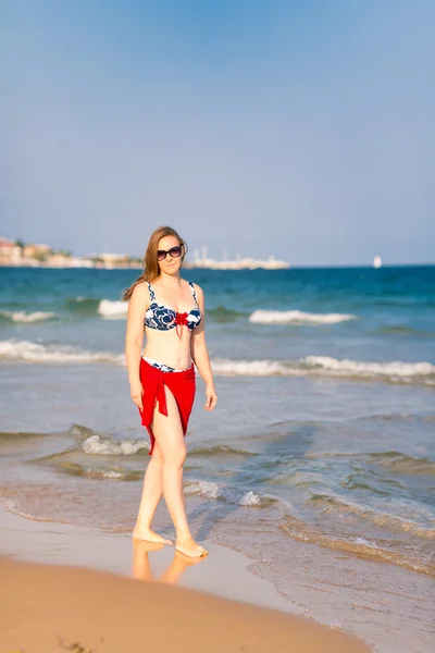 Krásná žena s červeným šátkem na pláži — Stock fotografie