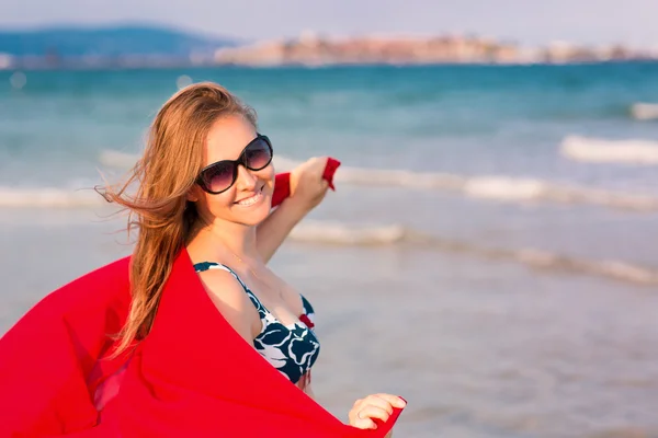 Όμορφη γυναίκα με κόκκινο κασκόλ στην παραλία — Φωτογραφία Αρχείου