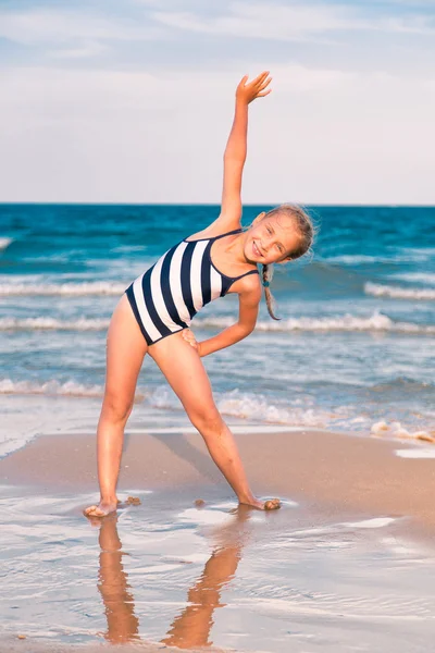 Vakker liten jente som øver på stranda – stockfoto