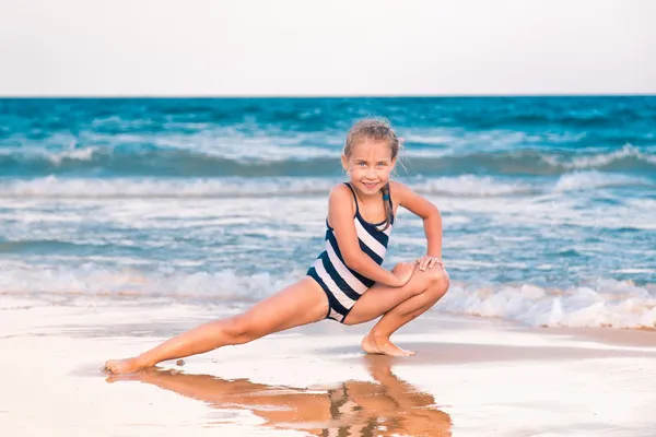 Hermosa niña haciendo ejercicio en la playa — Foto de Stock