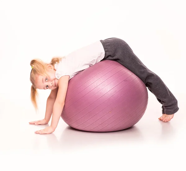 Sportliche Mädchen auf einem fitten Ball isoliert über weiß — Stockfoto