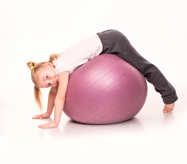 Menina esportiva em uma bola de ajuste isolado sobre branco — Fotografia de Stock