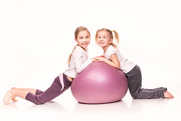 Meninas esportivas em uma bola de ajuste isolado sobre branco — Fotografia de Stock