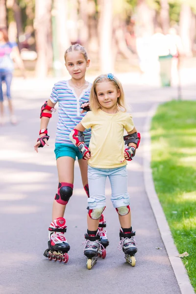 Two little girls rollerskating in the park — Stock Photo, Image