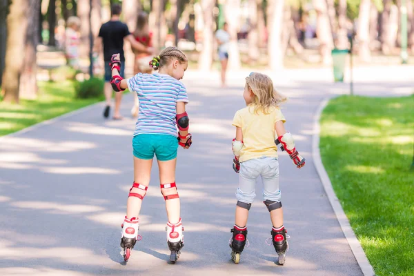 Two little girls rollerskating in the park — Stock Photo, Image