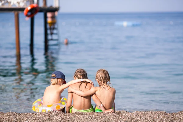 Tres niños sentados en una playa — Foto de Stock