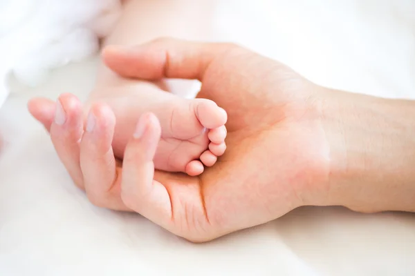 Vader houden van de voet van zijn pasgeboren zoon — Stockfoto