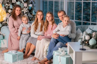 Büyük mutlu bir aile ve bir sürü çocuk Noel ağacının yanındaki kanepede eğleniyorlar. Noel arifesi, Noel ruh hali konsepti